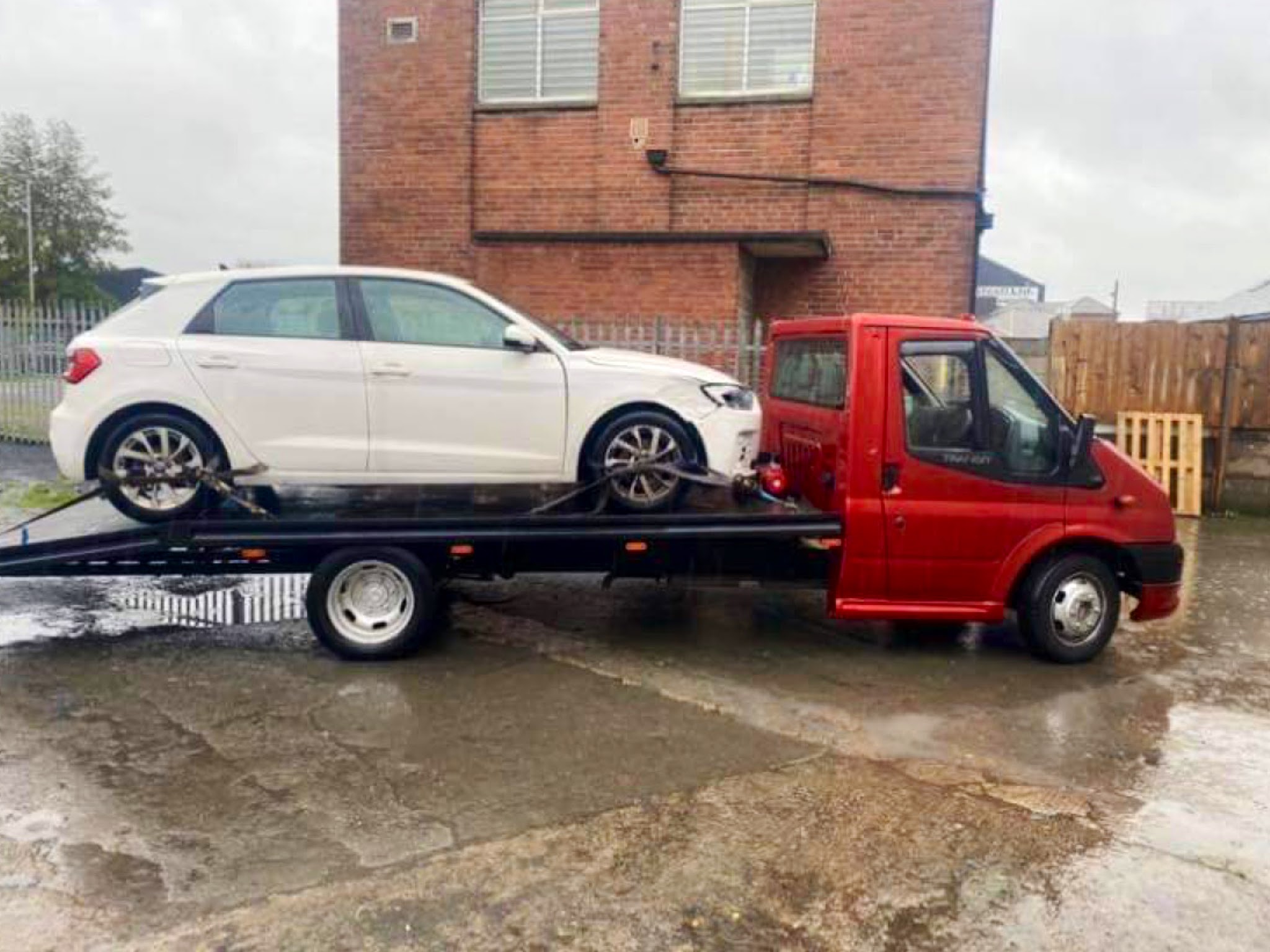 Recovery truck carrying a damaged white hatchback