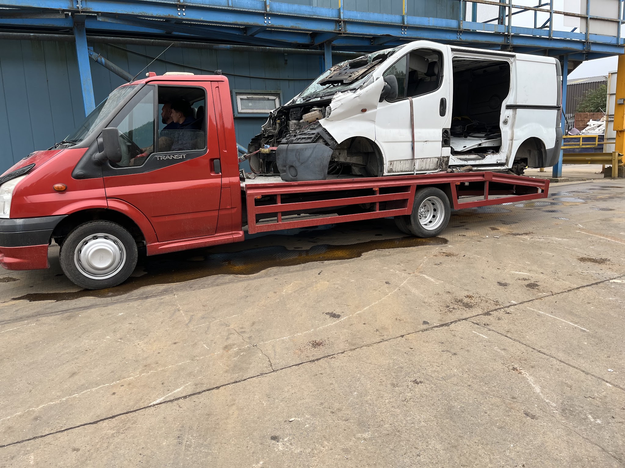 Recovery truck carrying a badly damaged white van
